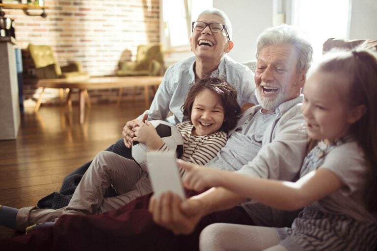 A group of people sitting on a couch with a cell phone.