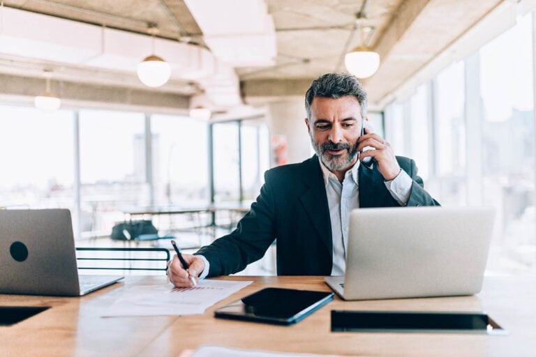 A businessman talking on the phone while sitting at a desk.