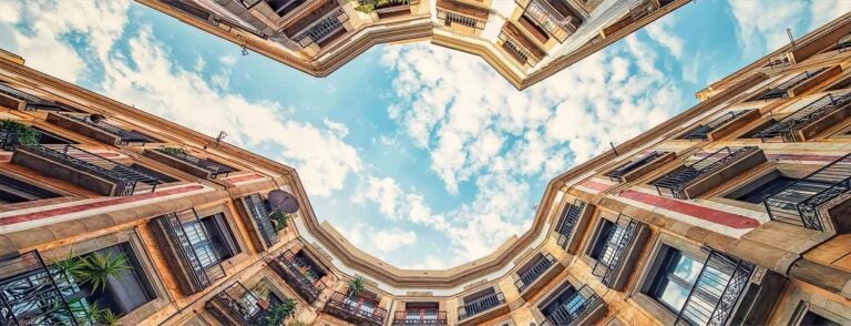 A curve between buildings shows the sky above, in Barcelona, Spain